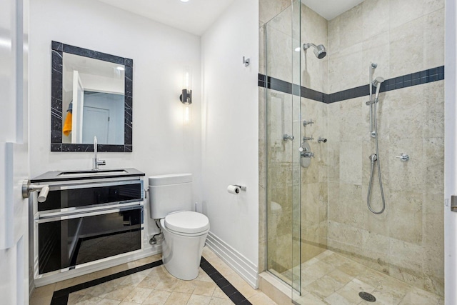 bathroom with a stall shower, toilet, vanity, and baseboards