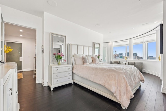 bedroom featuring a city view, recessed lighting, baseboards, and dark wood-style flooring