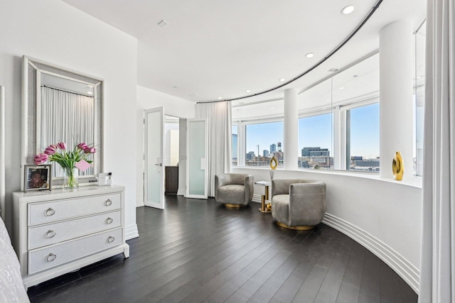 sitting room with recessed lighting, baseboards, a city view, and dark wood finished floors