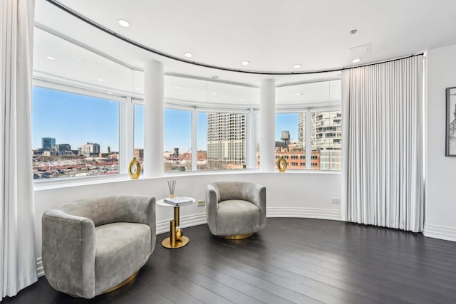 living area with a city view, hardwood / wood-style flooring, recessed lighting, and baseboards