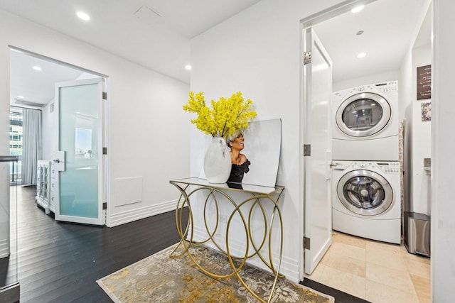 washroom with baseboards, stacked washer and dryer, laundry area, recessed lighting, and wood finished floors