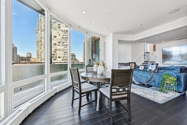 dining space with a view of city, wood finished floors, floor to ceiling windows, recessed lighting, and stairway