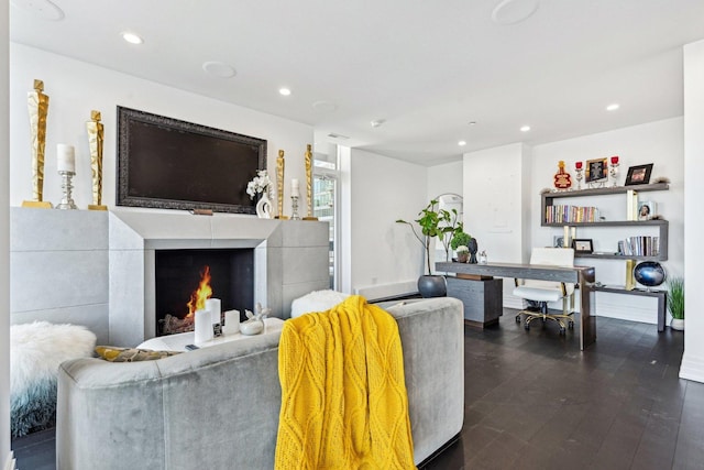 living area with recessed lighting, dark wood-style flooring, and a warm lit fireplace