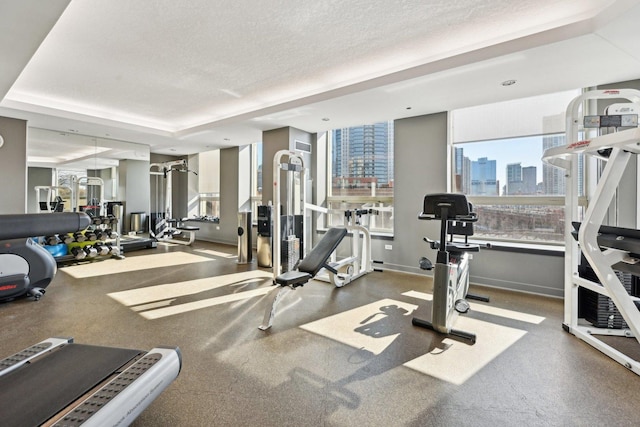 gym featuring a view of city, baseboards, and a textured ceiling