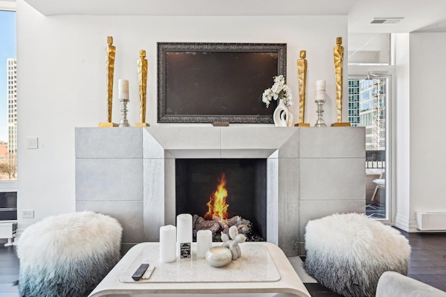 interior details featuring visible vents, a warm lit fireplace, and wood finished floors