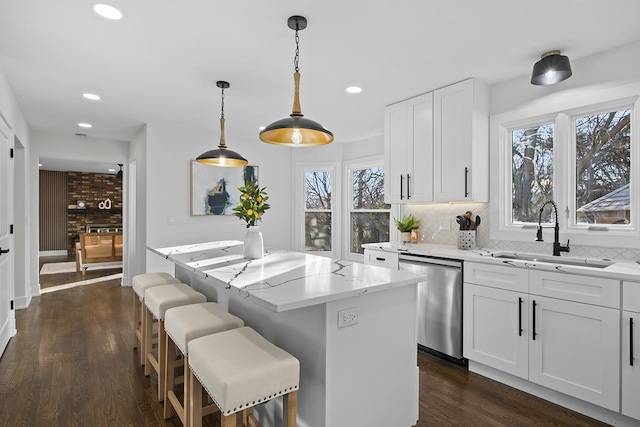 kitchen with sink, dishwasher, white cabinetry, hanging light fixtures, and a kitchen island