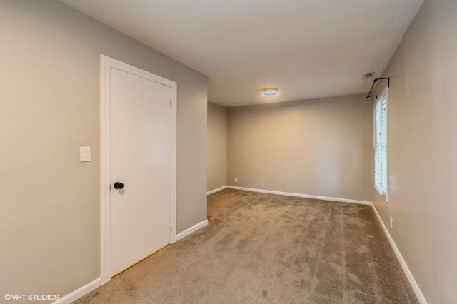 empty room with baseboards and light colored carpet