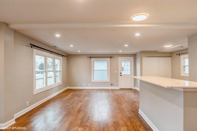 spare room with a wealth of natural light, dark wood finished floors, and baseboards