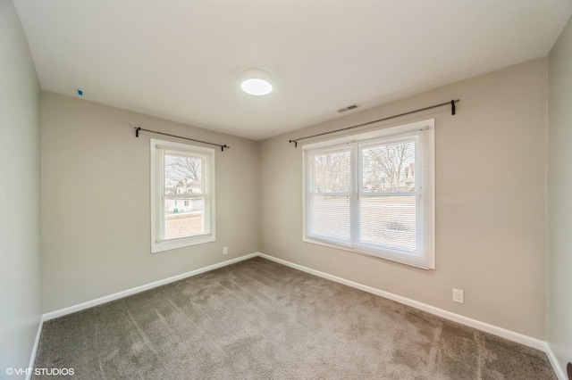 unfurnished room with visible vents, carpet flooring, a wealth of natural light, and baseboards