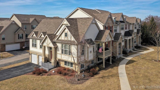 view of front of property featuring aphalt driveway, a residential view, a front yard, a shingled roof, and a garage