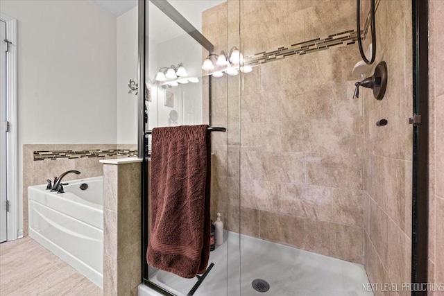 bathroom featuring wood finished floors, a bath, and a shower stall