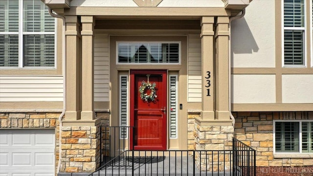 view of exterior entry with a garage and stone siding