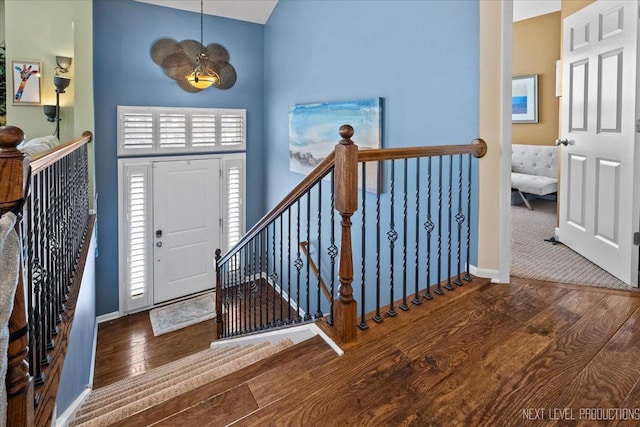 foyer entrance with baseboards, a high ceiling, and hardwood / wood-style flooring