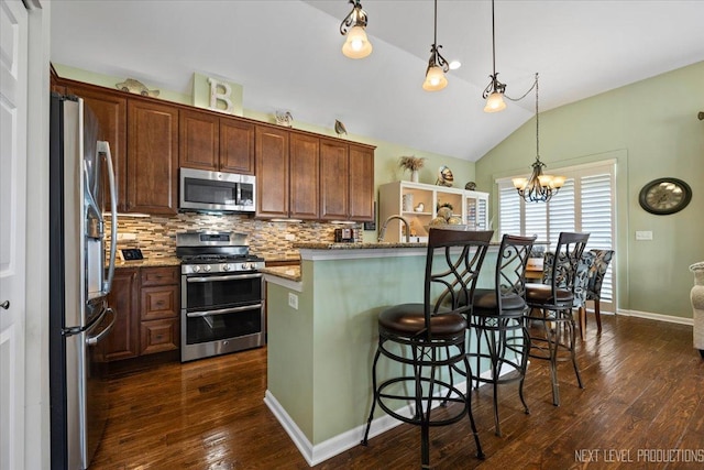 kitchen featuring a kitchen breakfast bar, backsplash, appliances with stainless steel finishes, dark wood-style flooring, and vaulted ceiling