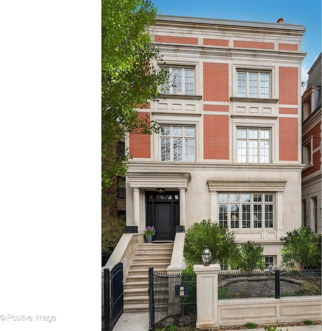townhome / multi-family property with a fenced front yard and brick siding