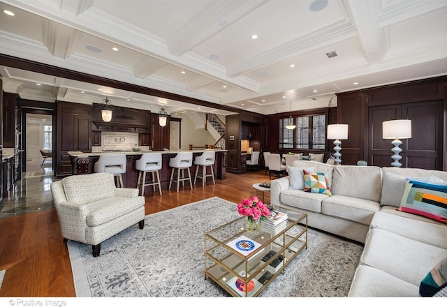 living room with coffered ceiling, ornamental molding, stairway, and wood finished floors