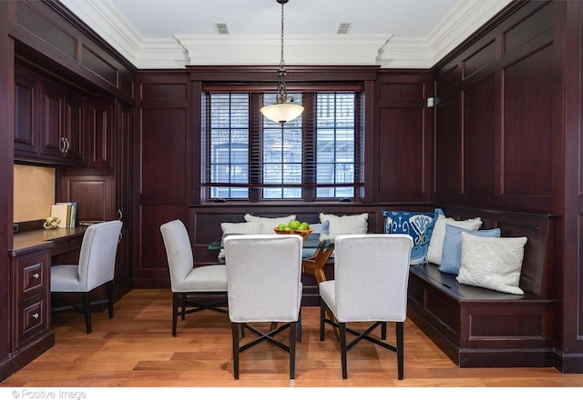 dining area with built in desk, light wood-style flooring, crown molding, and visible vents