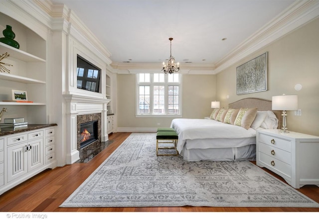 bedroom with a high end fireplace, an inviting chandelier, crown molding, and wood finished floors