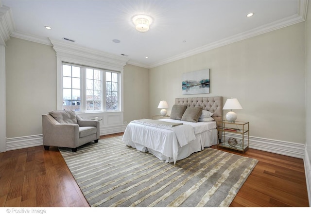 bedroom with crown molding, baseboards, visible vents, and wood finished floors