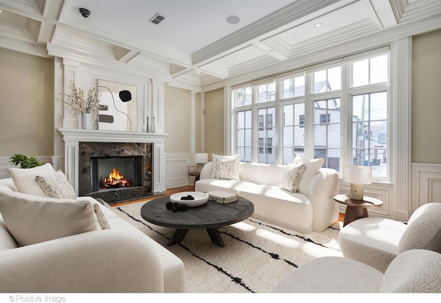 living area featuring a premium fireplace, a decorative wall, visible vents, and coffered ceiling