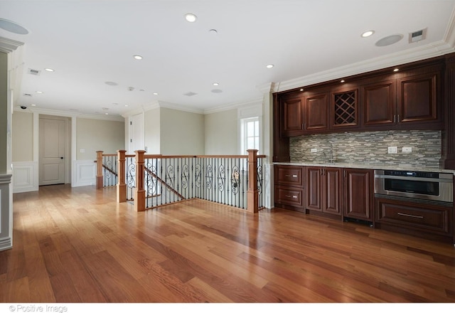 bar with ornamental molding, decorative backsplash, visible vents, and wood finished floors