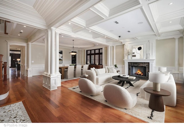 living area with a high end fireplace, ornamental molding, a decorative wall, and decorative columns