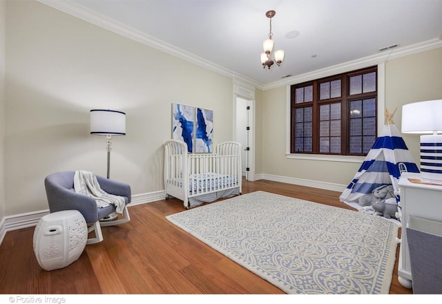 bedroom featuring crown molding, baseboards, a chandelier, and wood finished floors
