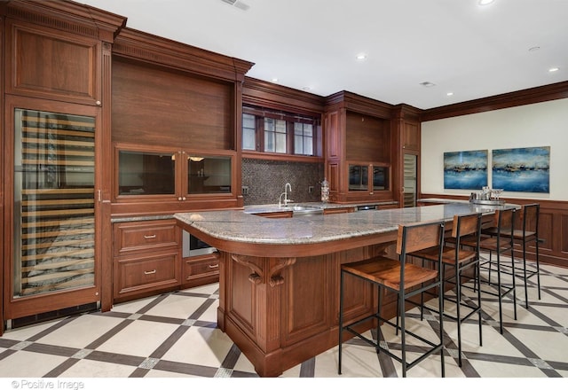 kitchen featuring recessed lighting, beverage cooler, glass insert cabinets, ornamental molding, and a kitchen breakfast bar