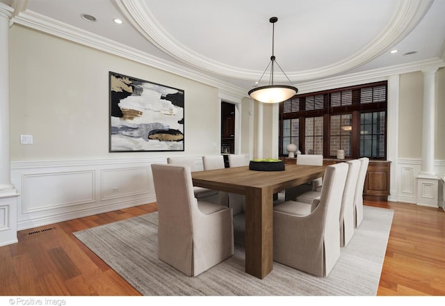 dining area with crown molding, light wood-type flooring, and ornate columns