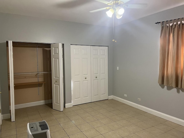 unfurnished bedroom with multiple closets, ceiling fan, and light tile patterned floors