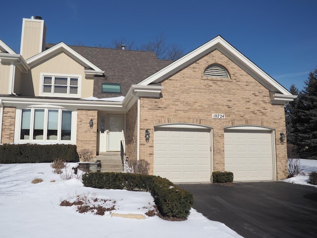 view of front facade featuring aphalt driveway, brick siding, and an attached garage