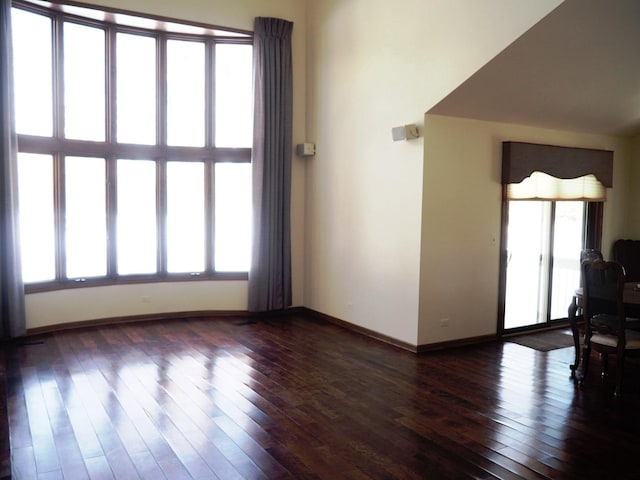 interior space featuring baseboards, dark wood-type flooring, and a healthy amount of sunlight