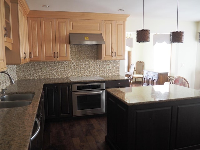 kitchen featuring stone counters, oven, electric cooktop, a sink, and wall chimney exhaust hood