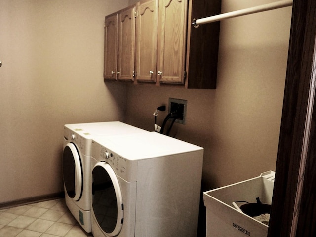 washroom featuring cabinet space, light tile patterned floors, baseboards, and washer and dryer