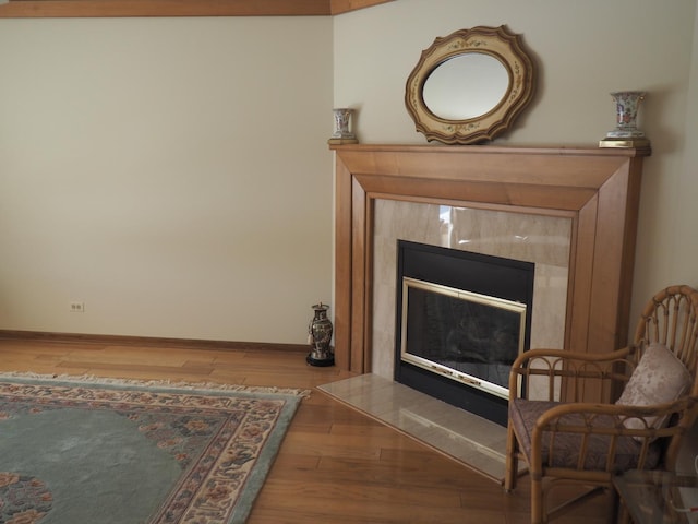 sitting room with a fireplace, wood finished floors, and baseboards