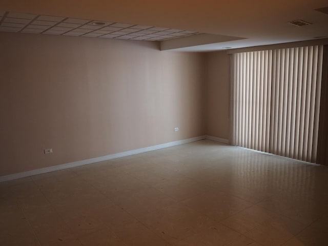 empty room featuring tile patterned floors, visible vents, and baseboards