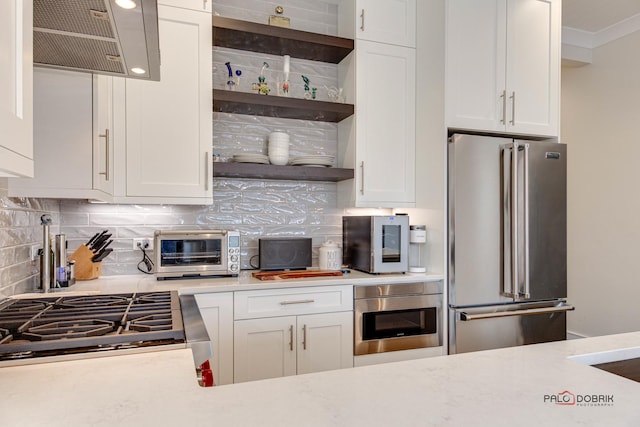 kitchen with appliances with stainless steel finishes, a toaster, light countertops, and decorative backsplash