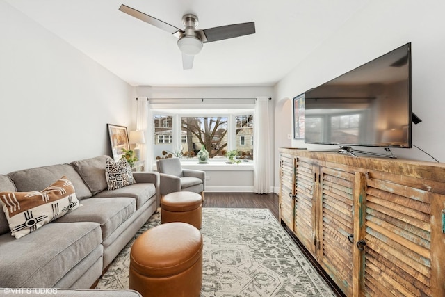 living room with dark wood finished floors, baseboards, and ceiling fan