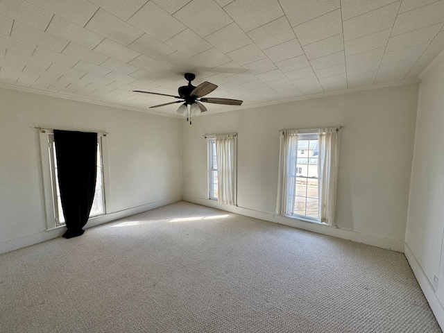 carpeted empty room featuring ceiling fan, ornamental molding, and baseboards