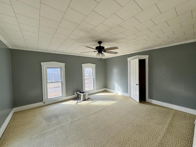 carpeted spare room featuring ceiling fan, ornamental molding, and baseboards