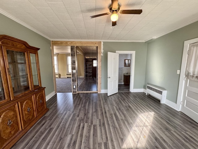 spare room with ornamental molding, radiator, baseboards, and dark wood-style flooring