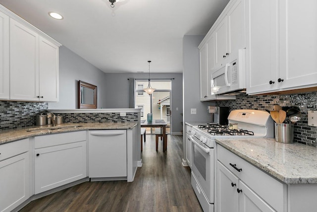 kitchen with pendant lighting, white appliances, backsplash, white cabinets, and dark hardwood / wood-style flooring