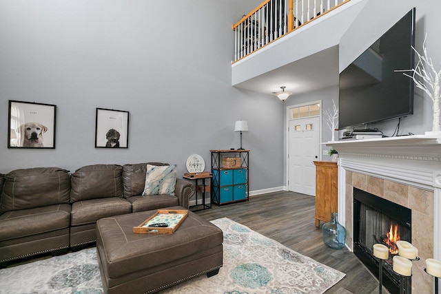 living room with a tiled fireplace, dark hardwood / wood-style floors, and a high ceiling