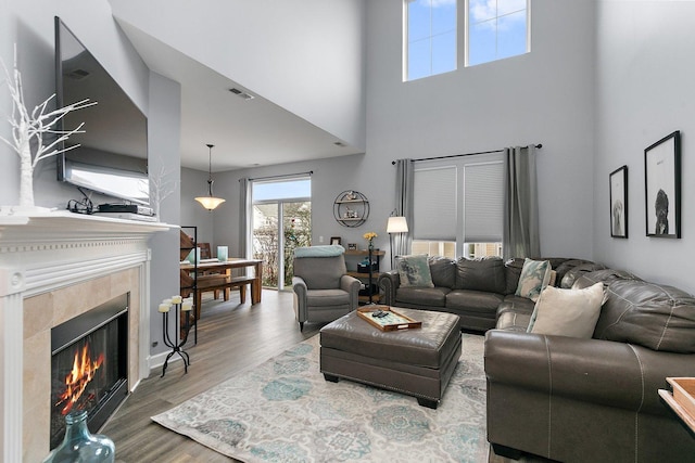 living room with hardwood / wood-style flooring, a fireplace, and a high ceiling