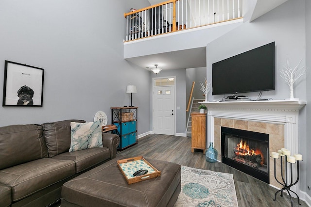 living room featuring a tile fireplace, dark wood-type flooring, and a towering ceiling