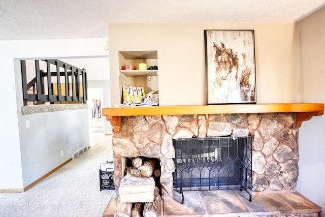 room details featuring a textured ceiling, a fireplace, visible vents, and carpet flooring