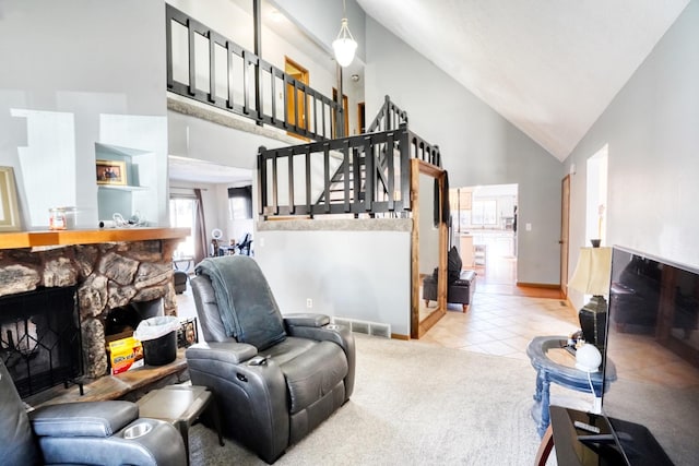 carpeted living room with high vaulted ceiling, a stone fireplace, visible vents, stairway, and tile patterned floors