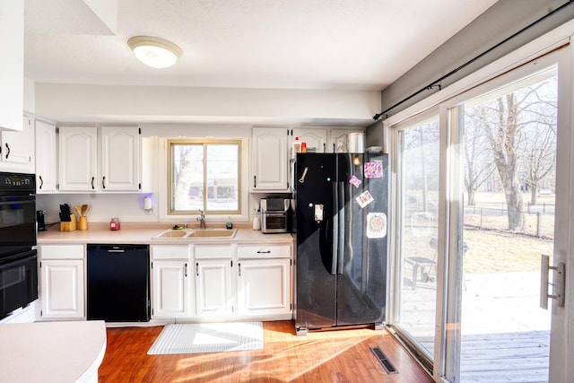 kitchen with plenty of natural light, visible vents, white cabinets, black appliances, and a sink