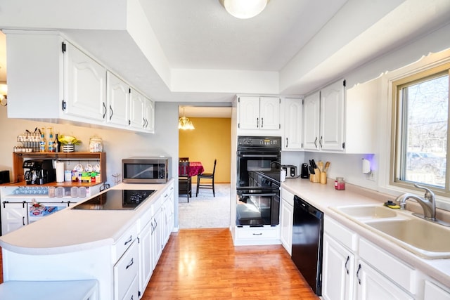 kitchen with black appliances, light countertops, a sink, and white cabinetry