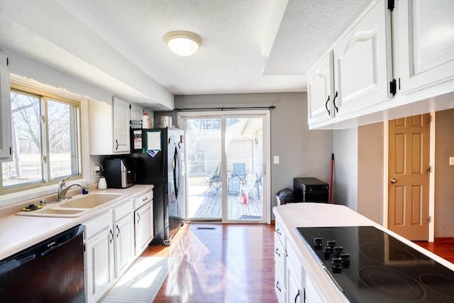 kitchen with a sink, white cabinets, light wood-style floors, light countertops, and black appliances